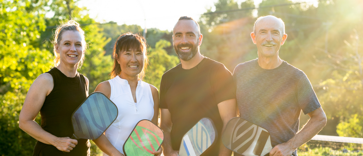 4 adults holding pickleball paddles