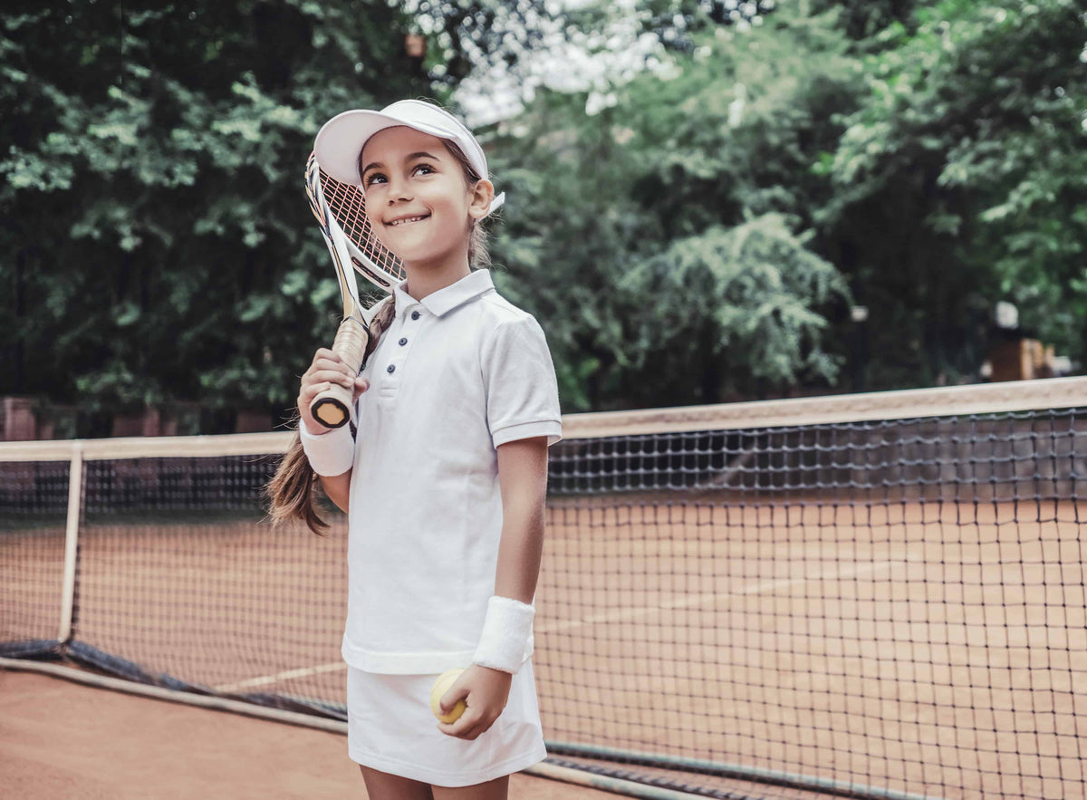 Child with tennis racquet on a clay court