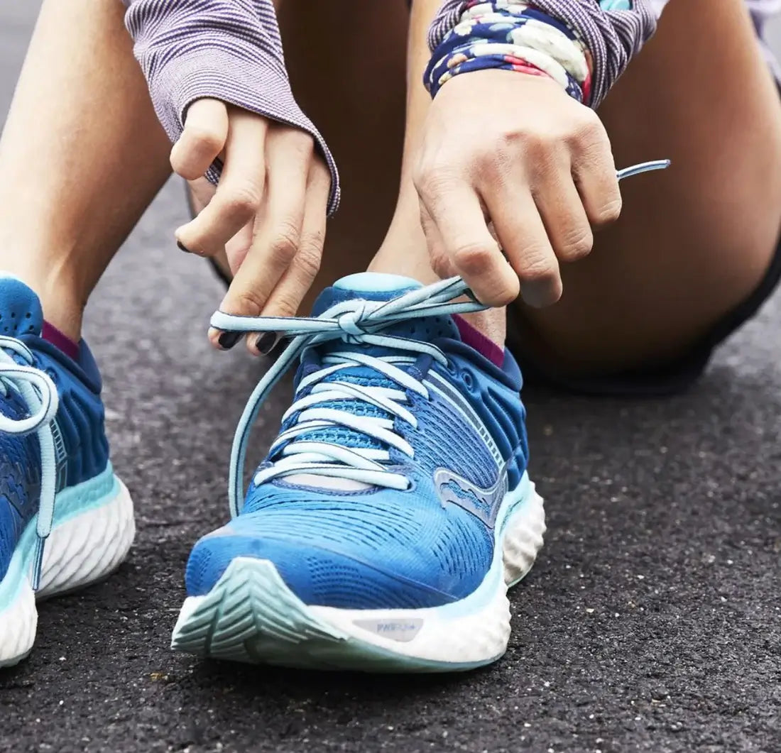 hands of a tennis player tying blue tennis shoes