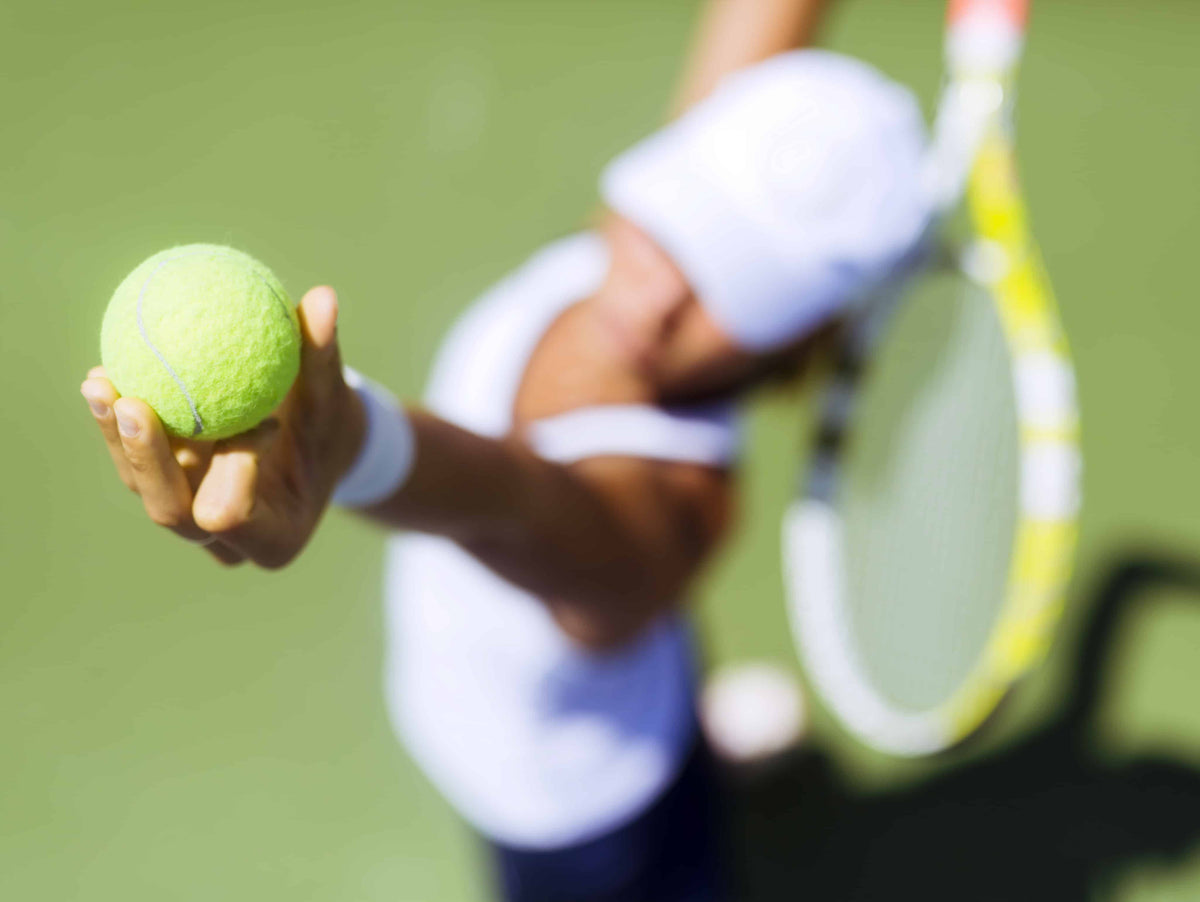 Woman serving tennis ball