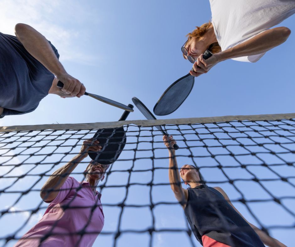4 pickleball players tapping paddles