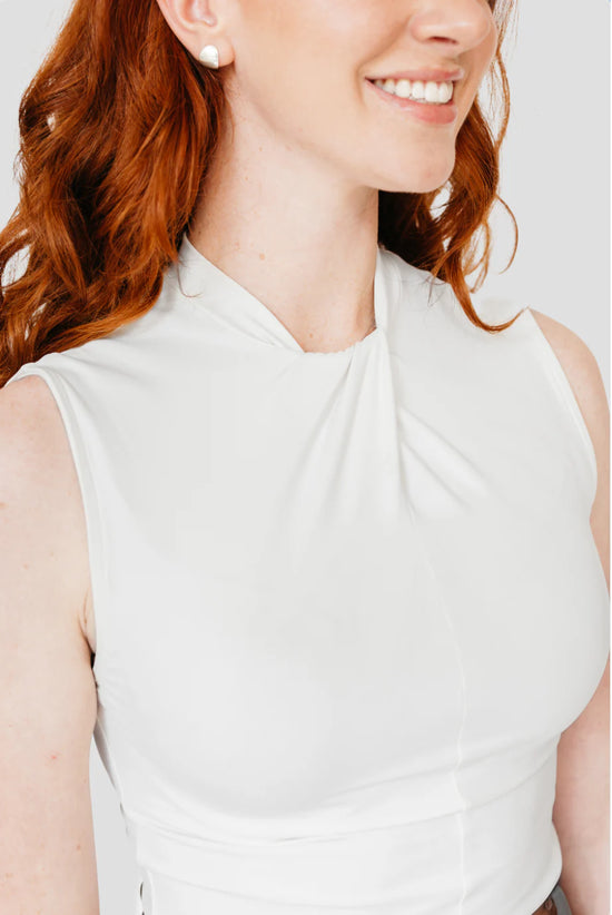 Woman wearing white top with a knotted collar detail