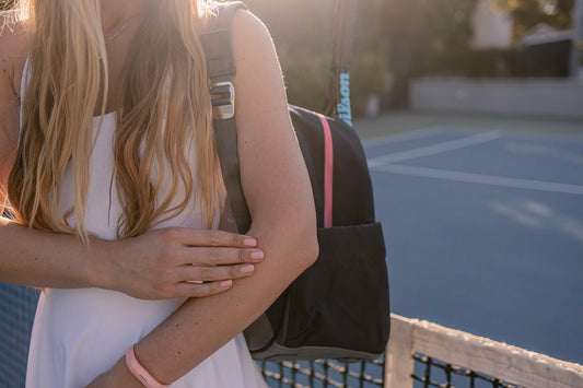 Woman rubbing her elbow on on a tennis court