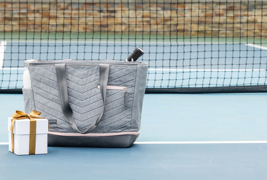 Parisii Doubletake Tote on tennis court with gift box next to it.