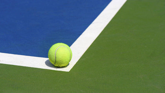 A woman wearing a workout top and tennis skirt holds a tennis racquet