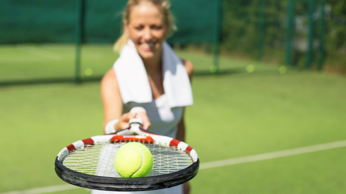 Woman showing tennis racquet with a ball on top of it