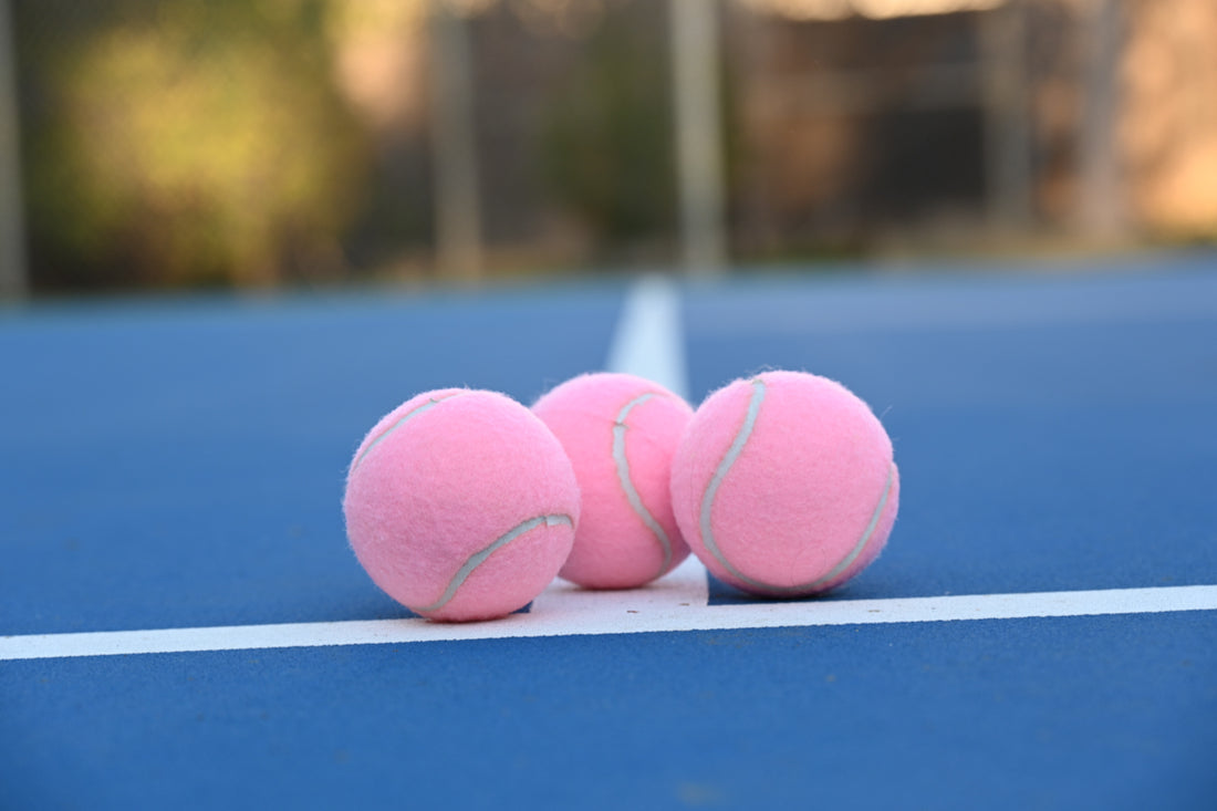 Three pink tennis balls on a blue court