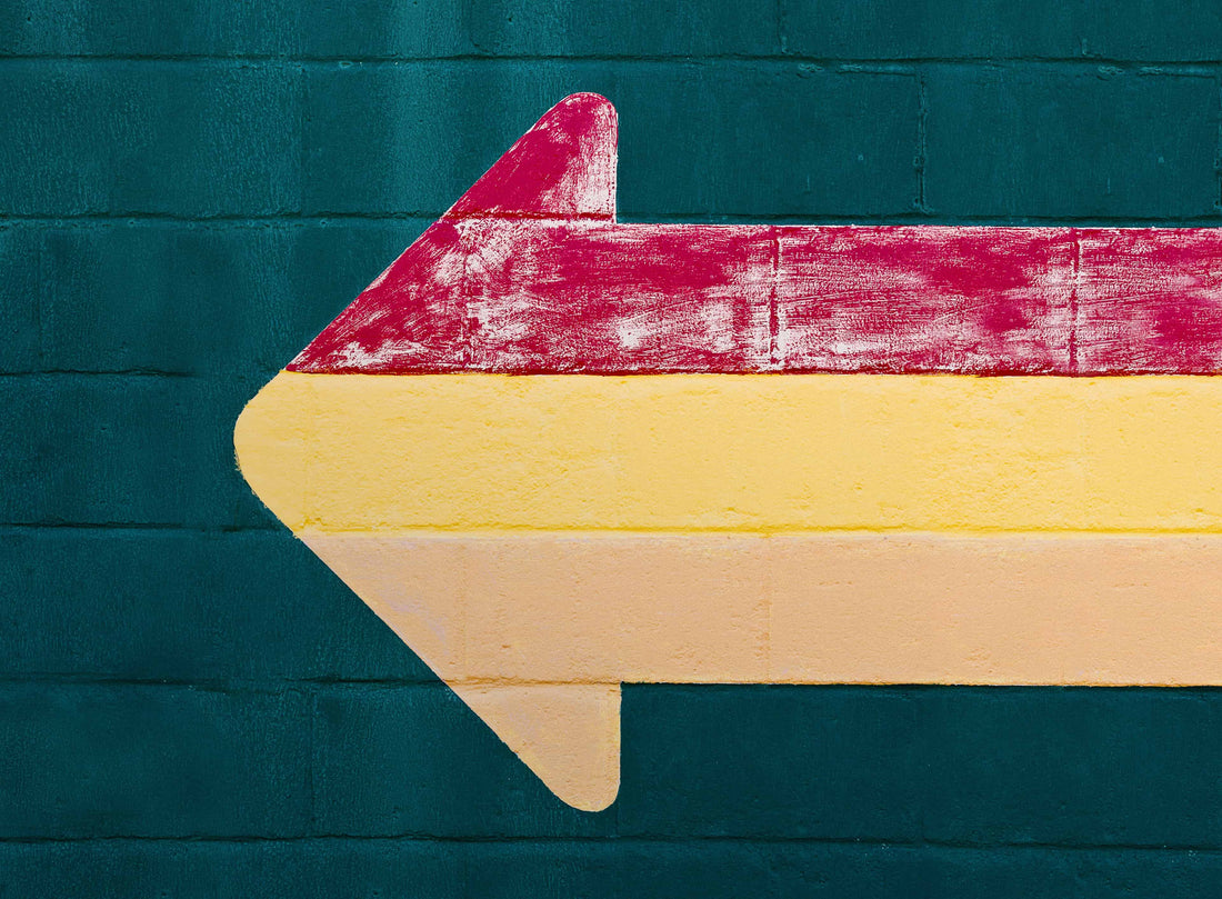 Red and yellow arrow painted on a concrete block wall.