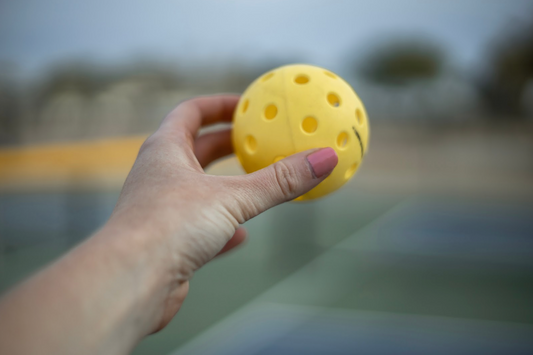 Woman holding a tennis ball in the air