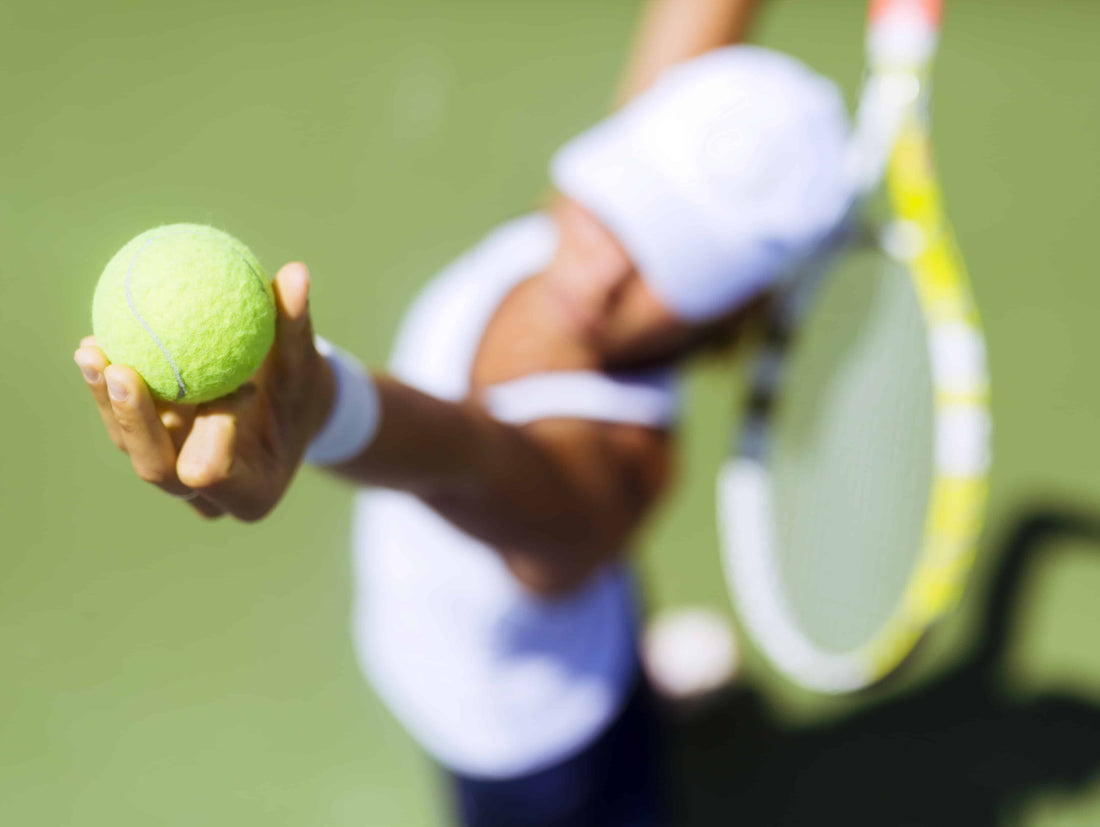 Woman serving tennis ball