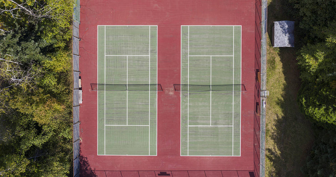 Ariel view of two tennis courts surrounded by trees