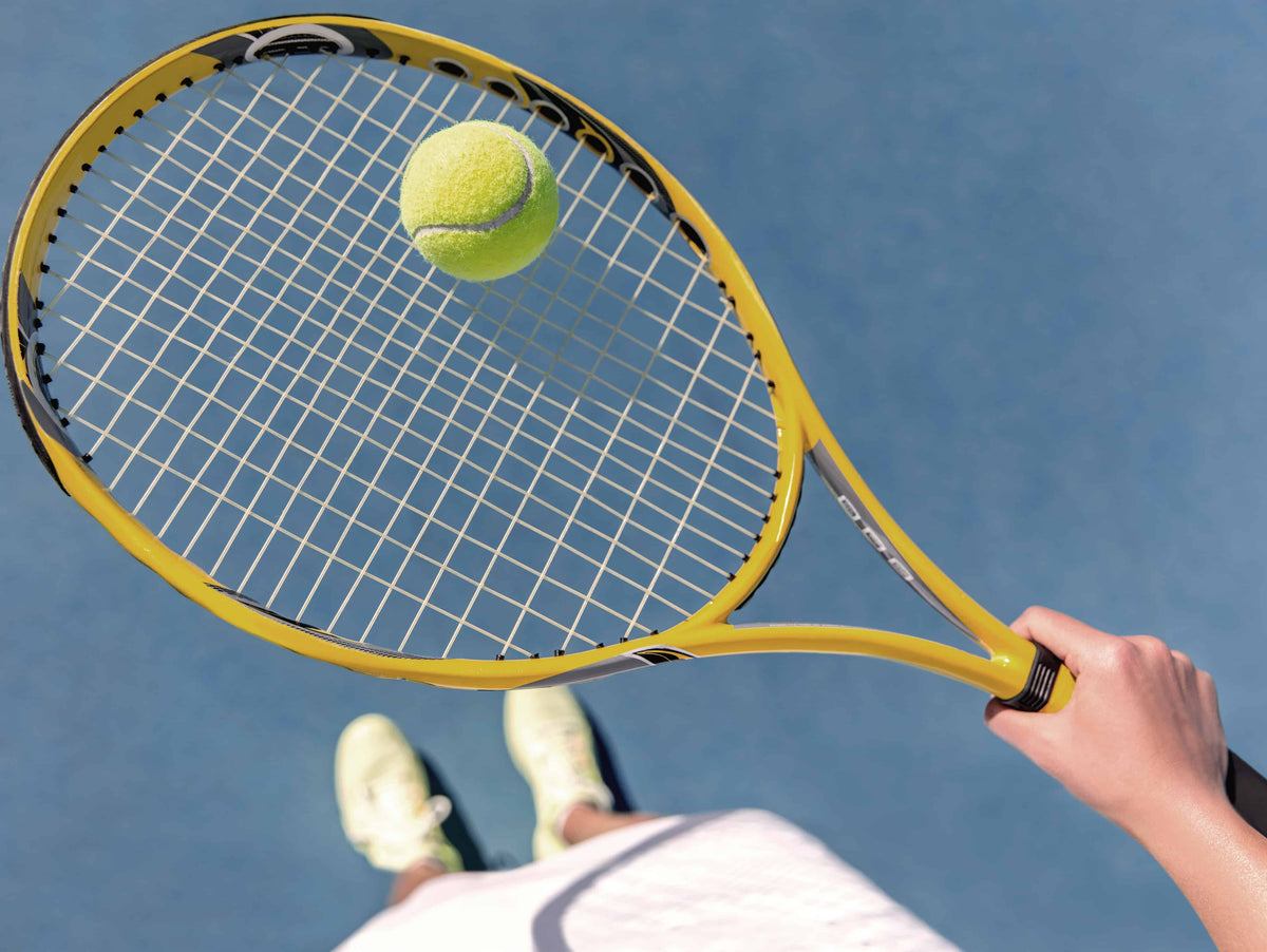 Woman balancing tennis ball on tennis racquet