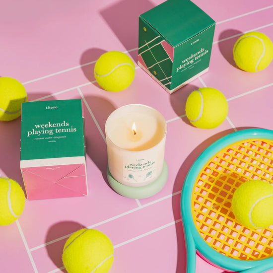 Tennis candle surrounded by tennis balls.