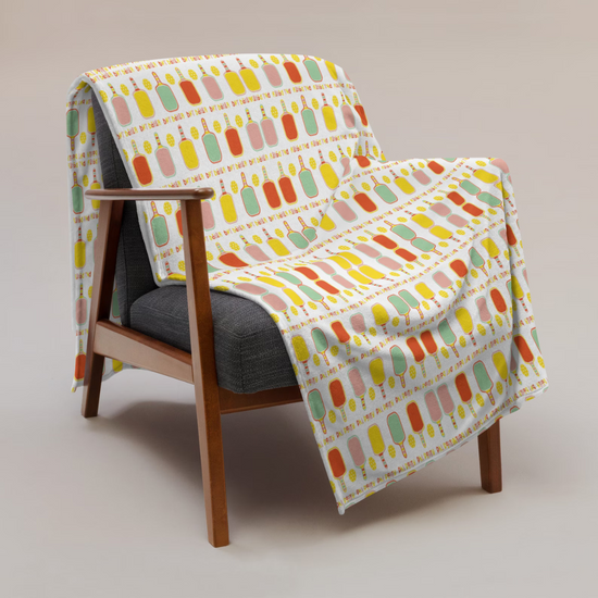 A wooden chair with a colorful popsicle-patterned blanket draped over it.