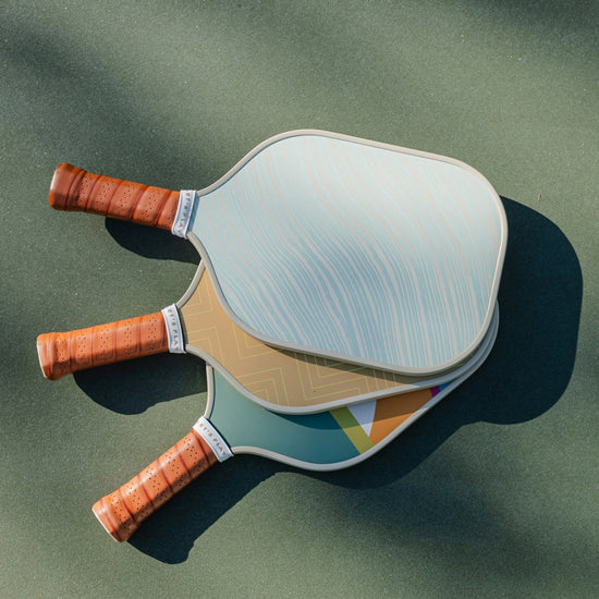 3 Pickleball paddles on court.