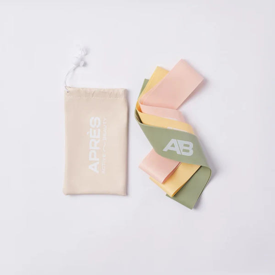 Three colorful resistance bands next to a beige pouch with the text APRÉS ACTIVE BEAUTY.