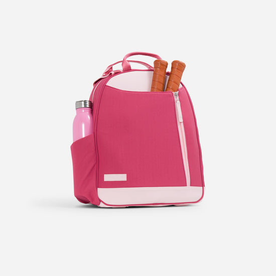 Pink tennis backpack with front pocket holding table tennis paddles and a side pocket with a pink water bottle.