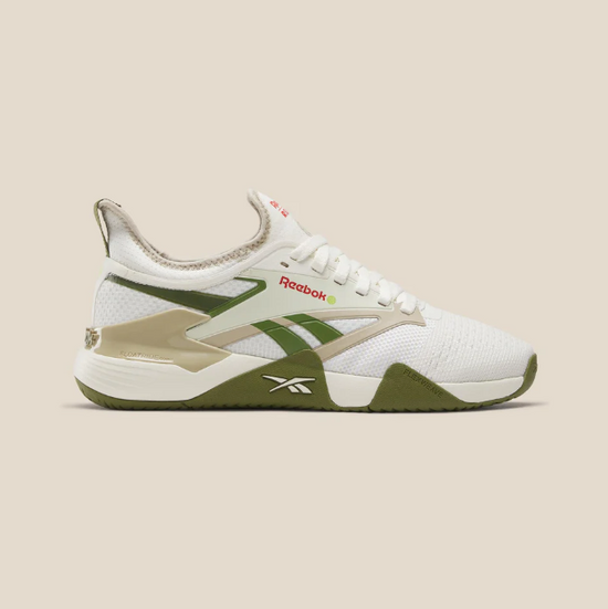 White and green Reebok sneaker with tan accents, side view on a beige background.