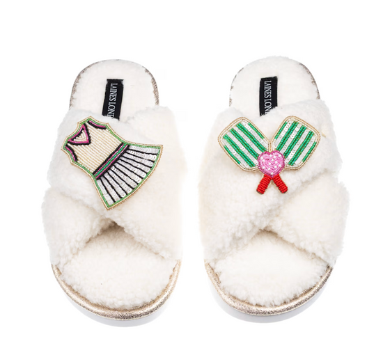 Plush neutral slippers decorated with pickleball-themed brooch details.