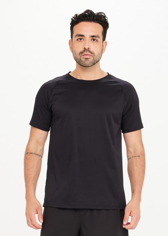 Man in a black T-shirt stands against a plain white background.