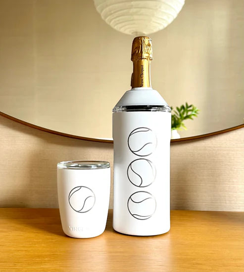 White insulated bottle and cup with abstract line designs, placed on a wooden surface in front of a round mirror.