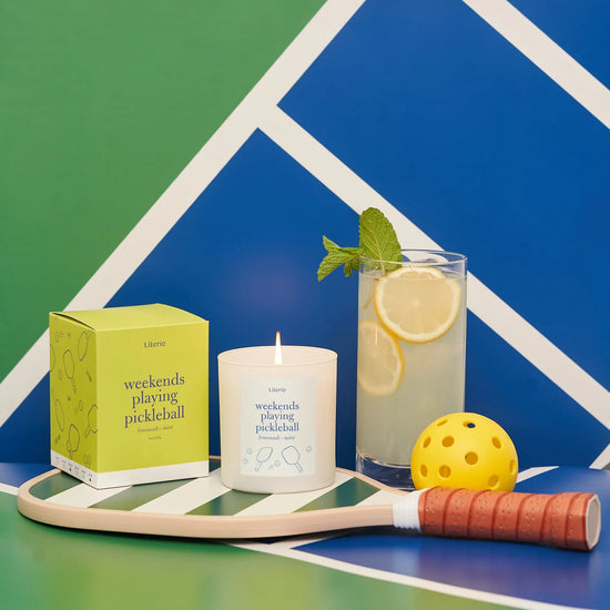Candle with a lemon mint drink and pickleball paddle and balls.