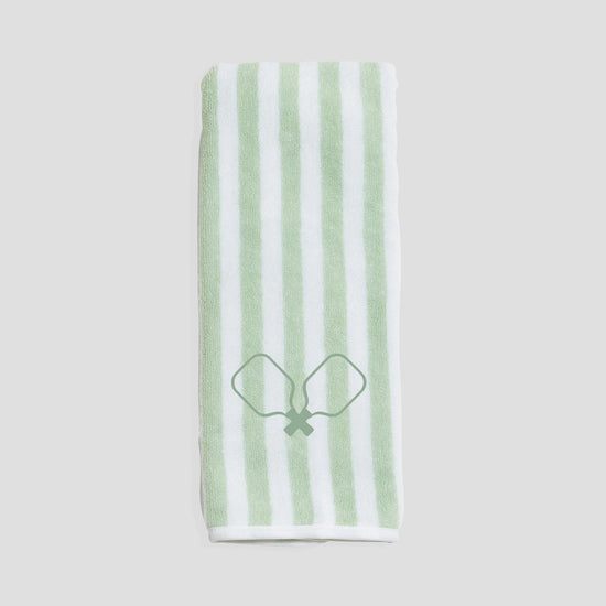 Folded white and green striped towel with crossed racquet design in the center on a plain background.