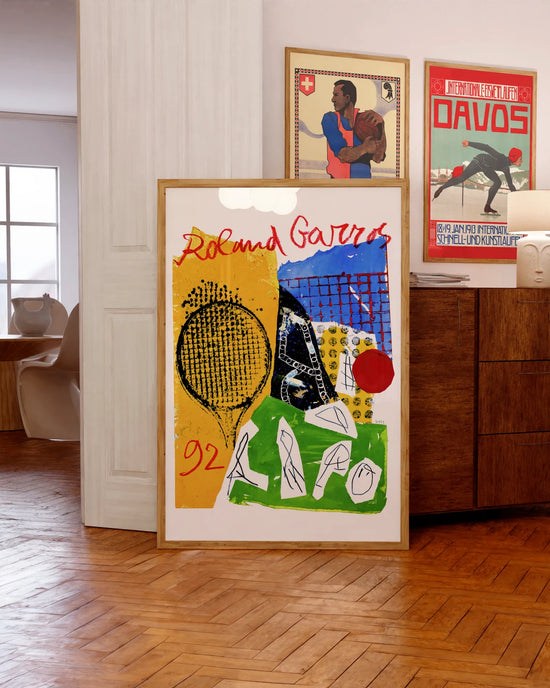 Framed Roland Garros poster with abstract design leans against a sideboard in a stylish, modern room.