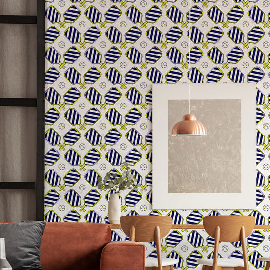 Room with patterned wallpaper, a reflective wall art piece, wooden chairs, and a small plant on a table.