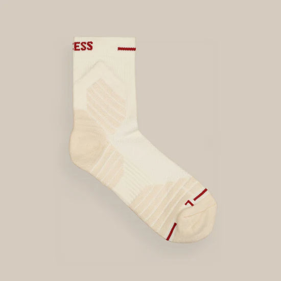 Cream-colored sock with red text near the cuff and red accents on the toe, heel, and edge, on a neutral background.